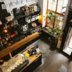 High angle view of a modern coffee shop interior with a wooden counter and cozy furnishings, ideal for business and leisure.