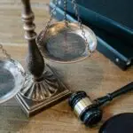 From above of judicial symbols consisting of Scales of Justice and small judge hammer with curly handle