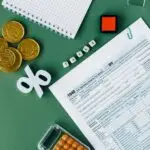 Tax documents and office supplies on green surface, indicating tax season planning and finance concepts.