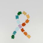 Colorful puzzle pieces arranged in awareness ribbon shape on white background.